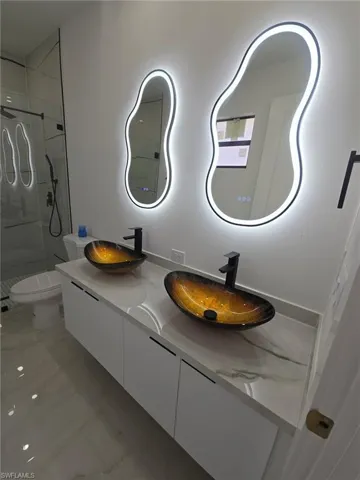 Full bath with double vanity, a marble finish shower, and recessed lighting