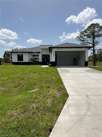 View of front facade featuring stucco siding, driveway, a garage, and a front yard