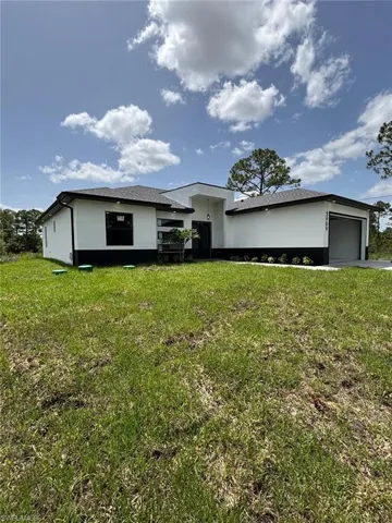 View of front of property with a front yard, an attached garage, and stucco siding