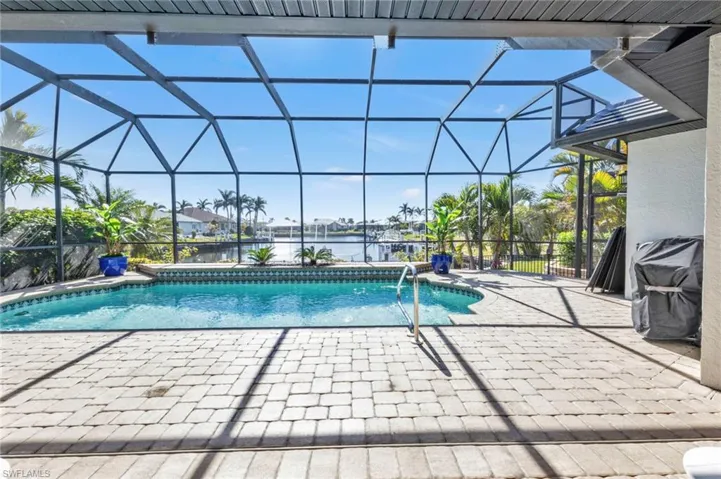 View of swimming pool featuring a water view, glass enclosure, and a patio