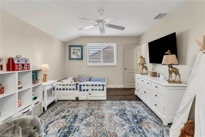 Bedroom featuring vaulted ceiling, dark hardwood / wood-style floors, and ceiling fan