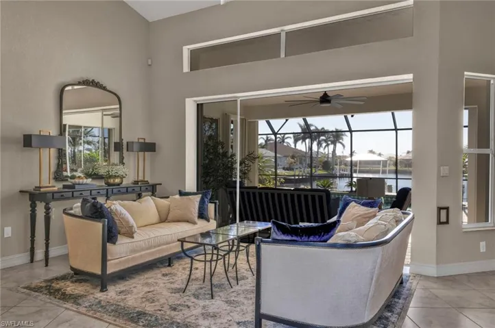 Living room with a water view, ceiling fan, tile patterned flooring, and a towering ceiling