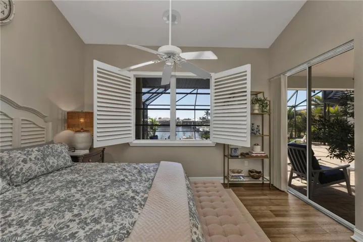 Bedroom with multiple windows, dark wood-type flooring, vaulted ceiling, and access to outside