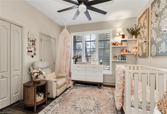 Bedroom featuring wood-type flooring, ceiling fan, and a nursery area