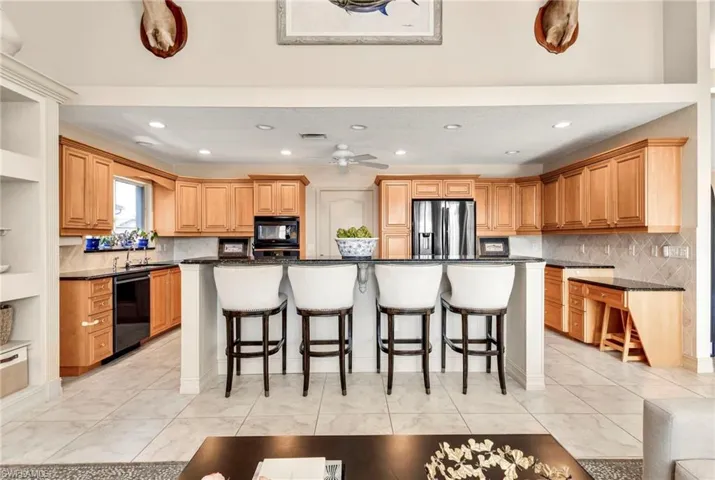 Kitchen with a breakfast bar area, a kitchen island, black appliances, and backsplash