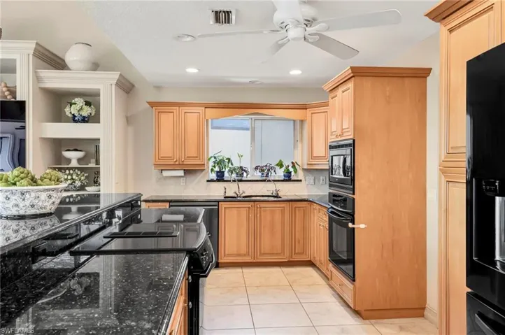 Kitchen with sink, dark stone countertops, black appliances, and decorative backsplash