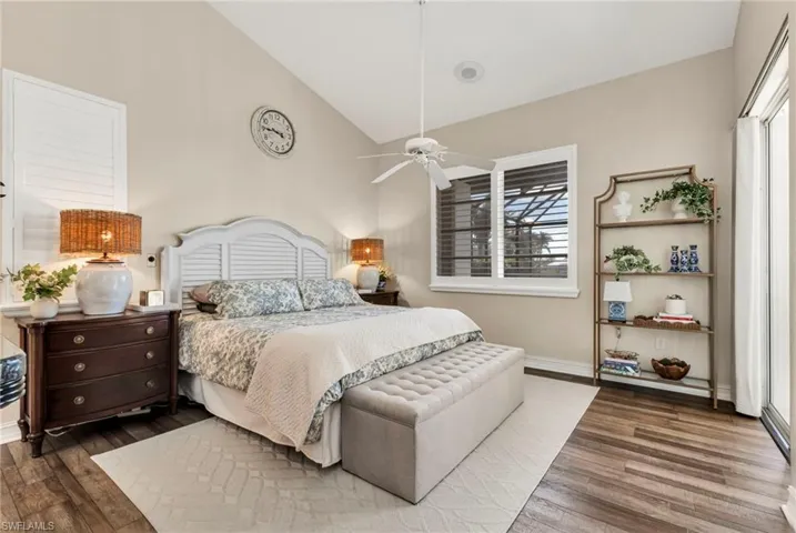 Bedroom with ceiling fan, high vaulted ceiling, multiple windows, and hardwood / wood-style floors
