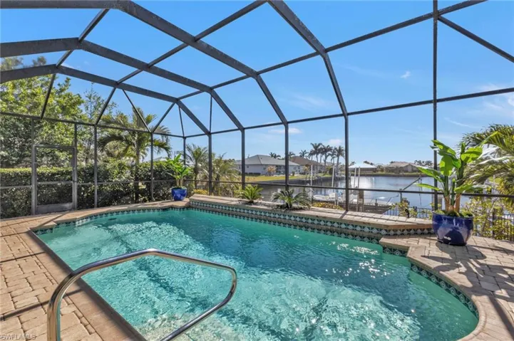 Pool featuring glass enclosure, a water view, and a patio