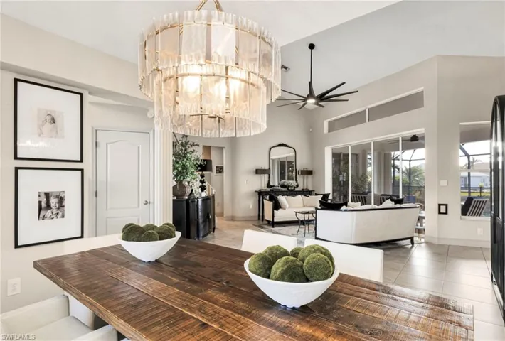 Dining room with a towering ceiling, light tile patterned flooring, and ceiling fan with notable chandelier