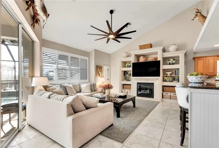 Living room featuring ceiling fan and high vaulted ceiling