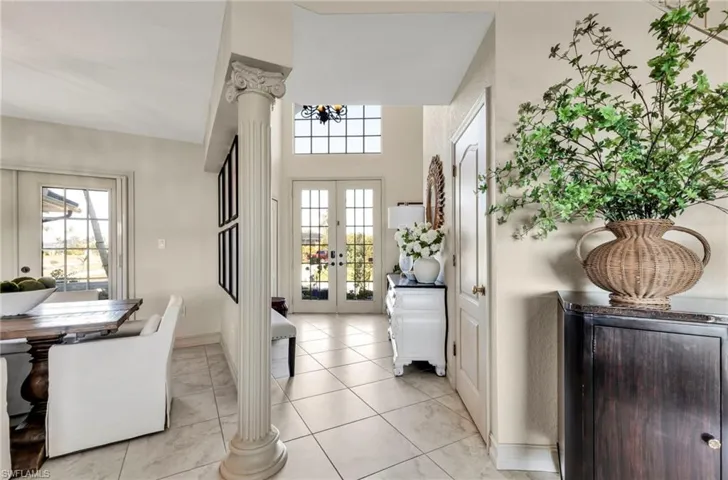 Doorway to outside with light tile patterned floors, decorative columns, french doors, and a healthy amount of sunlight