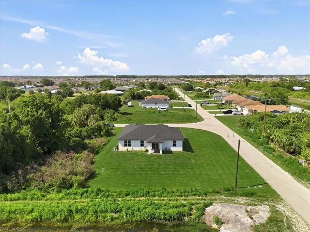The property features a ranch-style home with a dark shingle roof, situated on a large grassy lot