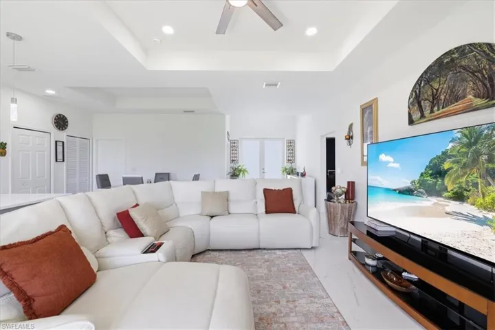 The living area features a white sectional sofa, a rug with a geometric pattern, and white tile flooring