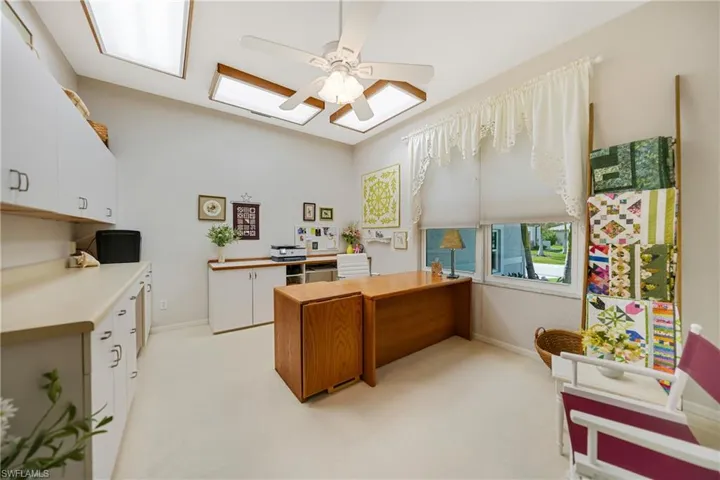 Home office with light carpet and ceiling fan