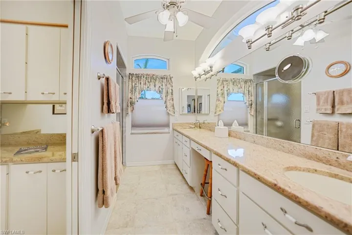 Bathroom with vanity, ceiling fan, tile flooring, and an enclosed shower