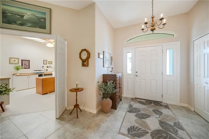 Entrance foyer featuring high vaulted ceiling, ceiling fan with notable chandelier, and light tile patterned floors