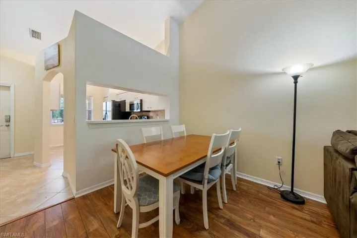Dining room featuring visible vents, arched walkways, baseboards, and wood finished floors