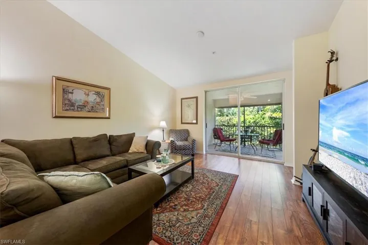 Living room with baseboards, vaulted ceiling, and dark wood-type flooring