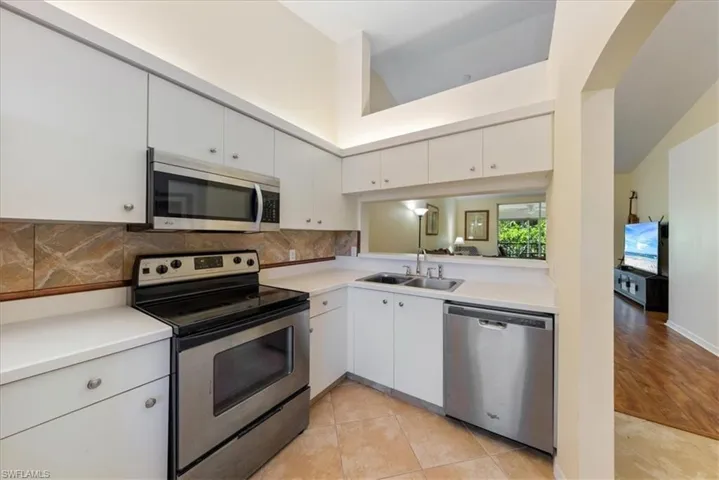 Kitchen featuring a sink, appliances with stainless steel finishes, backsplash, and light countertops