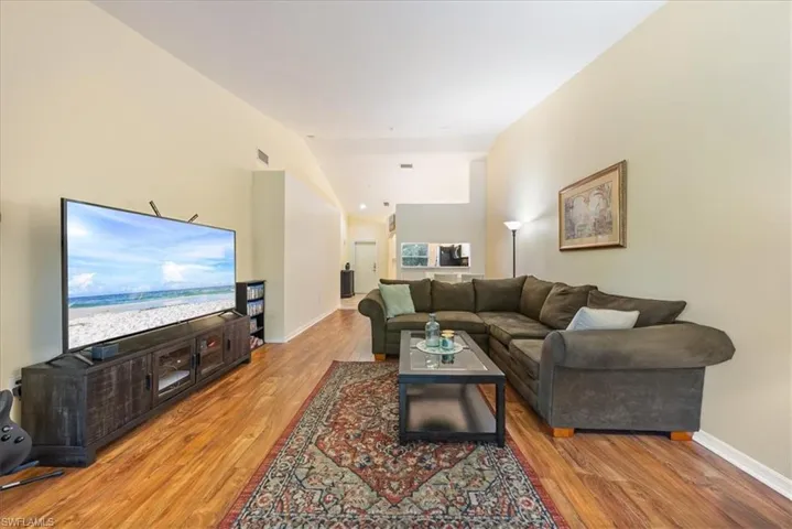 Living area with baseboards, vaulted ceiling, wood finished floors, and visible vents