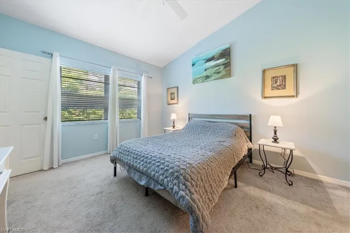 Carpeted bedroom featuring baseboards, vaulted ceiling, and ceiling fan