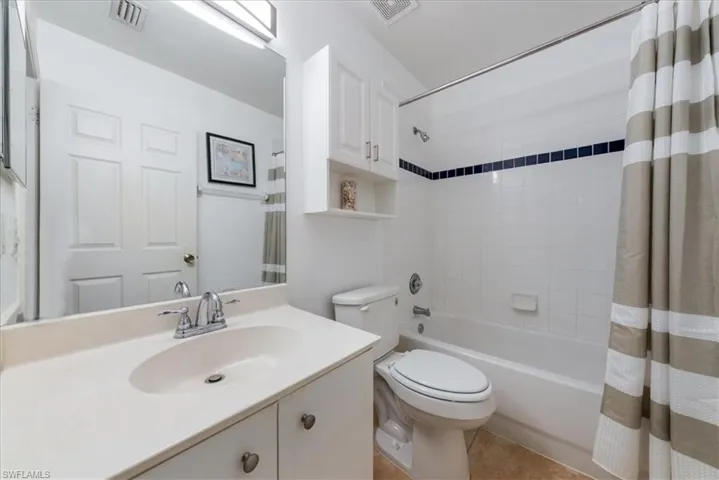 Full bathroom featuring shower / tub combo with curtain, vanity, toilet, and visible vents