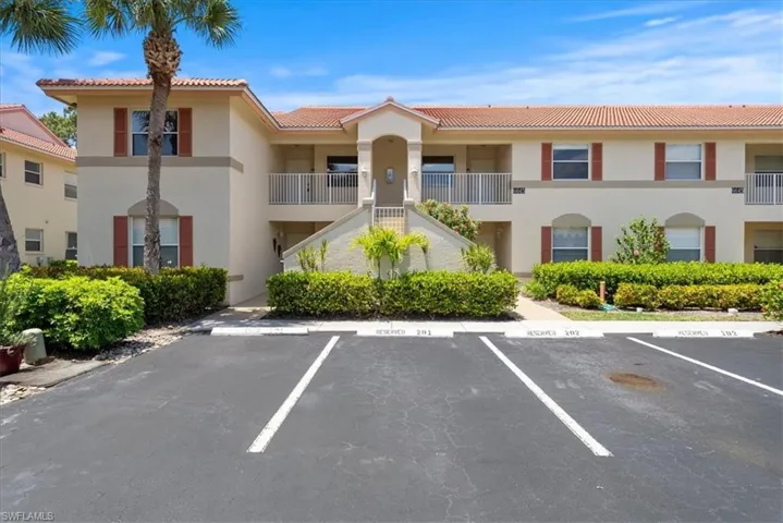 View of property with stairway and uncovered parking