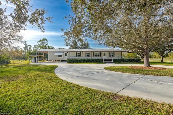 Circular concrete driveway leads to a tucked-away home, surrounded by fully fenced grounds and a picturesque pond.