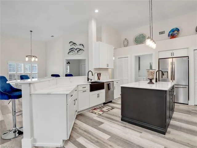 Open Kitchen with stainless steel appliances, granite countertops, white cabinets, island, breakfast bar and luxury vinyl flooring