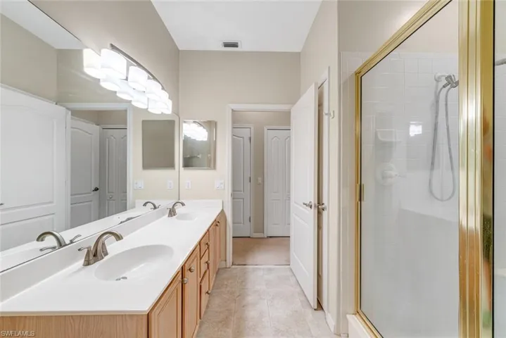 Bathroom with double vanity, a stall shower, and light tile patterned flooring