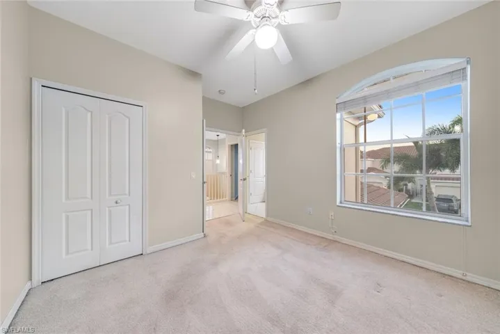 Unfurnished bedroom with light colored carpet, ceiling fan, and a closet