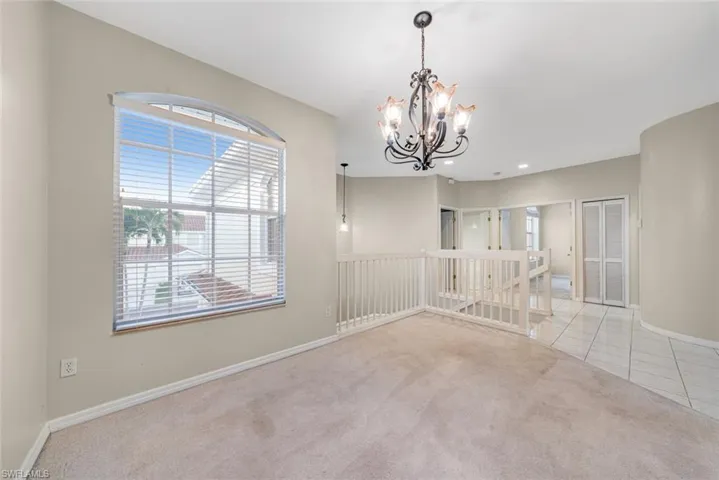 Tiled empty room with carpet, a chandelier, and recessed lighting