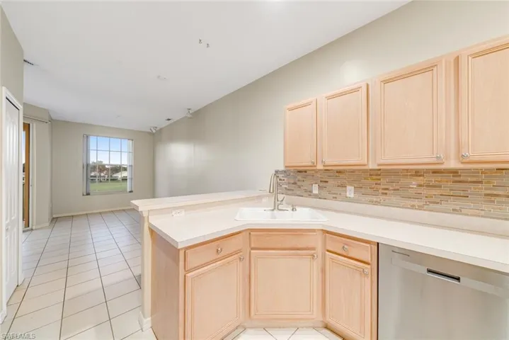 Kitchen with light brown cabinets, stainless steel dishwasher, and light countertops