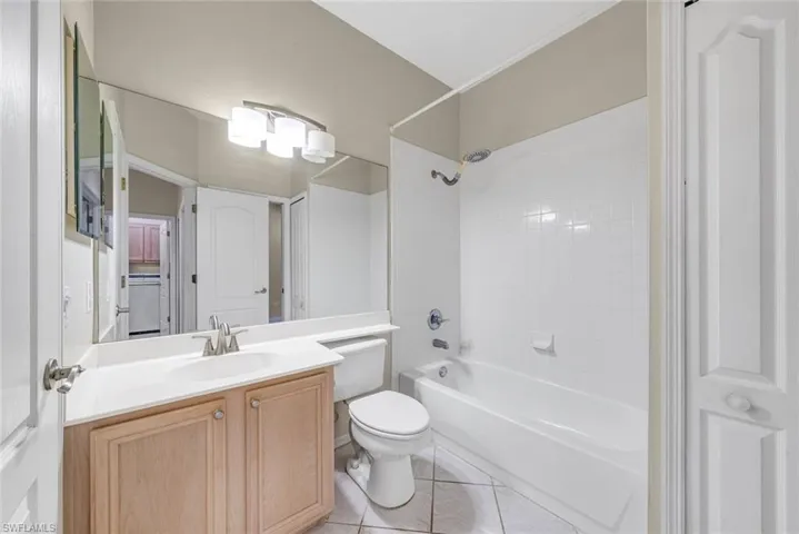 Full bath featuring vanity, washtub / shower combination, and light tile patterned flooring