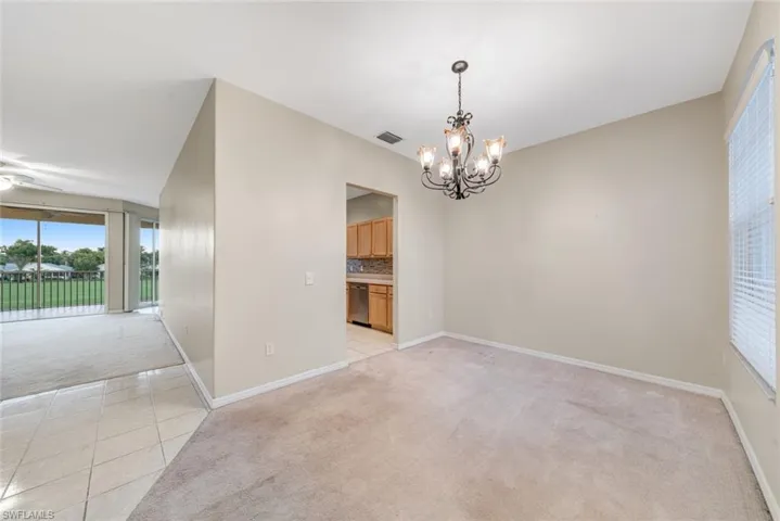 Unfurnished dining area featuring light carpet, light tile patterned flooring, a chandelier, and a ceiling fan