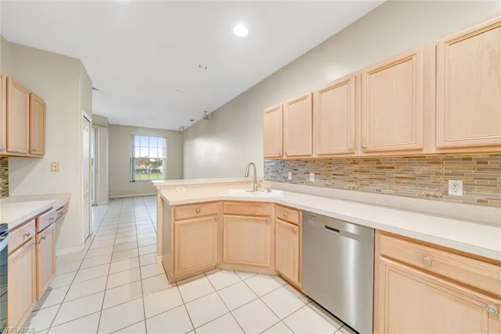 Kitchen with light brown cabinets, tasteful backsplash, dishwasher, light countertops, and a peninsula