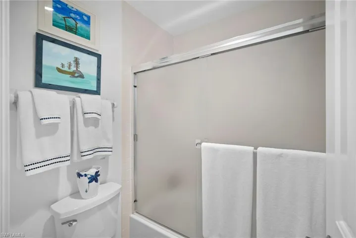 Bathroom featuring shower / bath combination with glass door and toilet