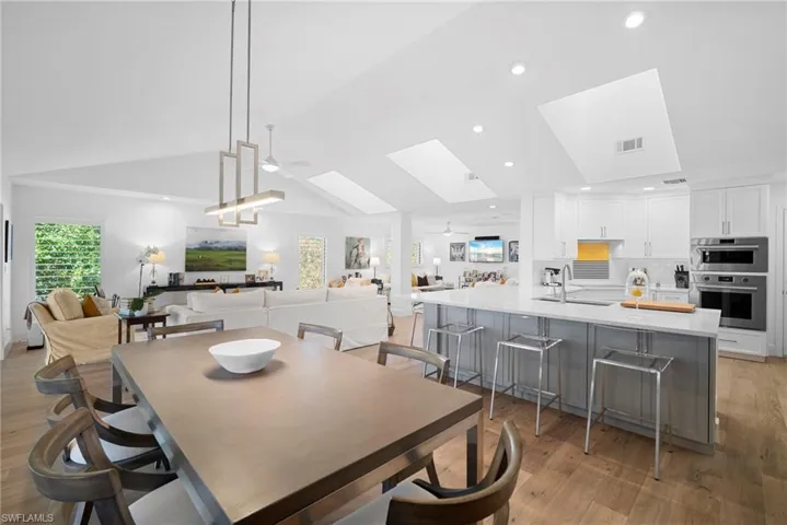 Dining space with light wood finished floors, ceiling fan, a skylight, a high ceiling, and recessed lighting