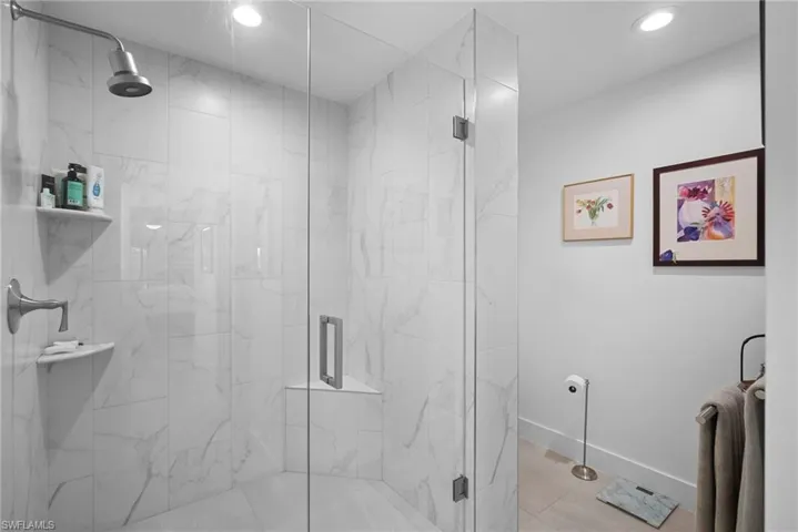 Bathroom with a marble finish shower and recessed lighting