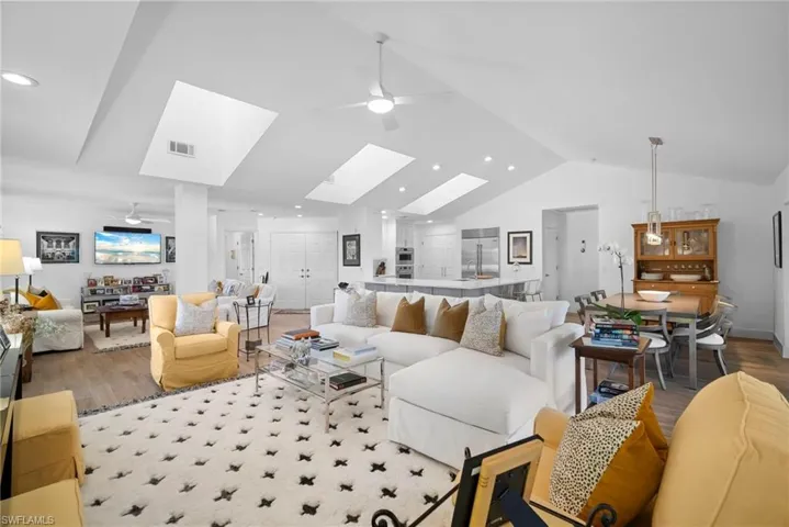 Living area with ceiling fan, wood finished floors, a skylight, lofted ceiling, and recessed lighting