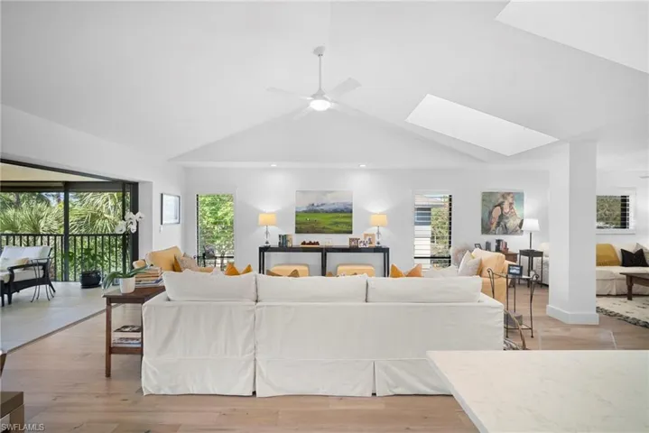 Living area with a ceiling fan, light wood-style flooring, and a skylight