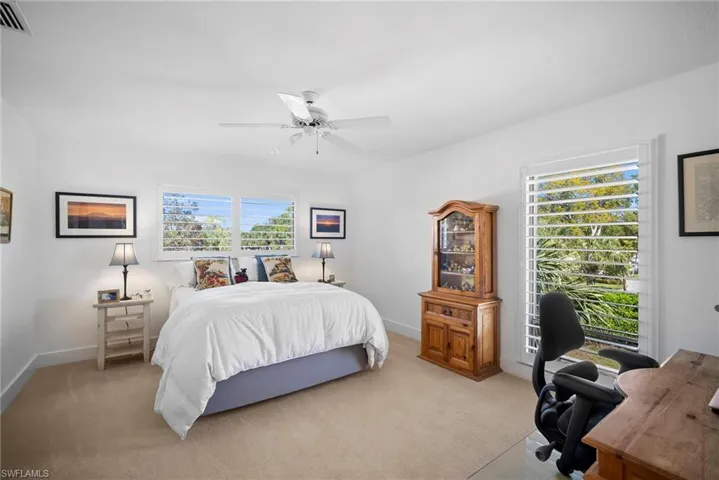 Carpeted bedroom featuring a desk and ceiling fan
