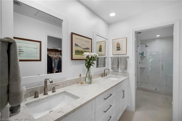 Full bath with double vanity, a marble finish shower, a walk in closet, and recessed lighting
