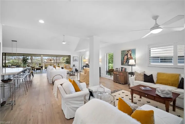 Living room with ceiling fan, light wood-style floors, healthy amount of natural light, lofted ceiling, and recessed lighting