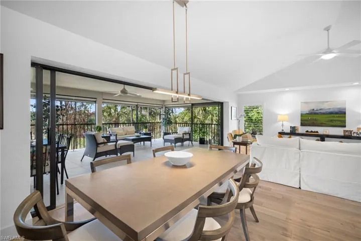 Dining space featuring a ceiling fan, vaulted ceiling, light wood-style floors, and plenty of natural light
