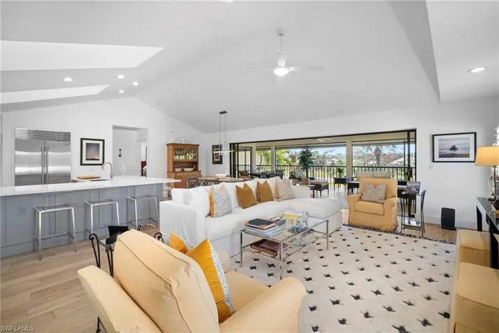 Living area featuring recessed lighting, vaulted ceiling, light wood-type flooring, a skylight, and a ceiling fan