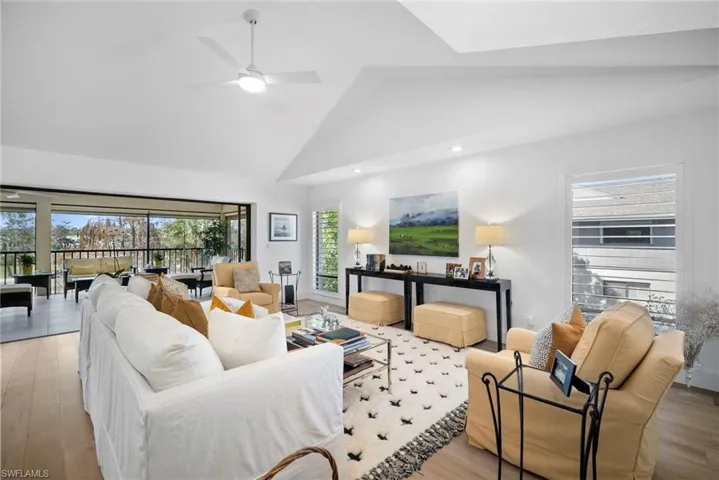 Living room with light wood finished floors, a ceiling fan, a high ceiling, and recessed lighting