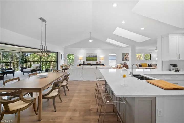 Kitchen featuring a ceiling fan, light stone countertops, light wood-type flooring, white cabinets, and hanging light fixtures