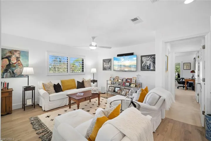 Living room featuring light wood-type flooring, ceiling fan, and plenty of natural light
