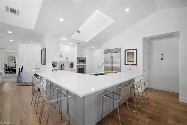 Kitchen with a breakfast bar area, light wood-style floors, a skylight, lofted ceiling, and recessed lighting